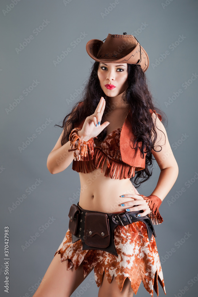 closeup beautiful brunette girl in frank cowboy costume and hat poses at camera