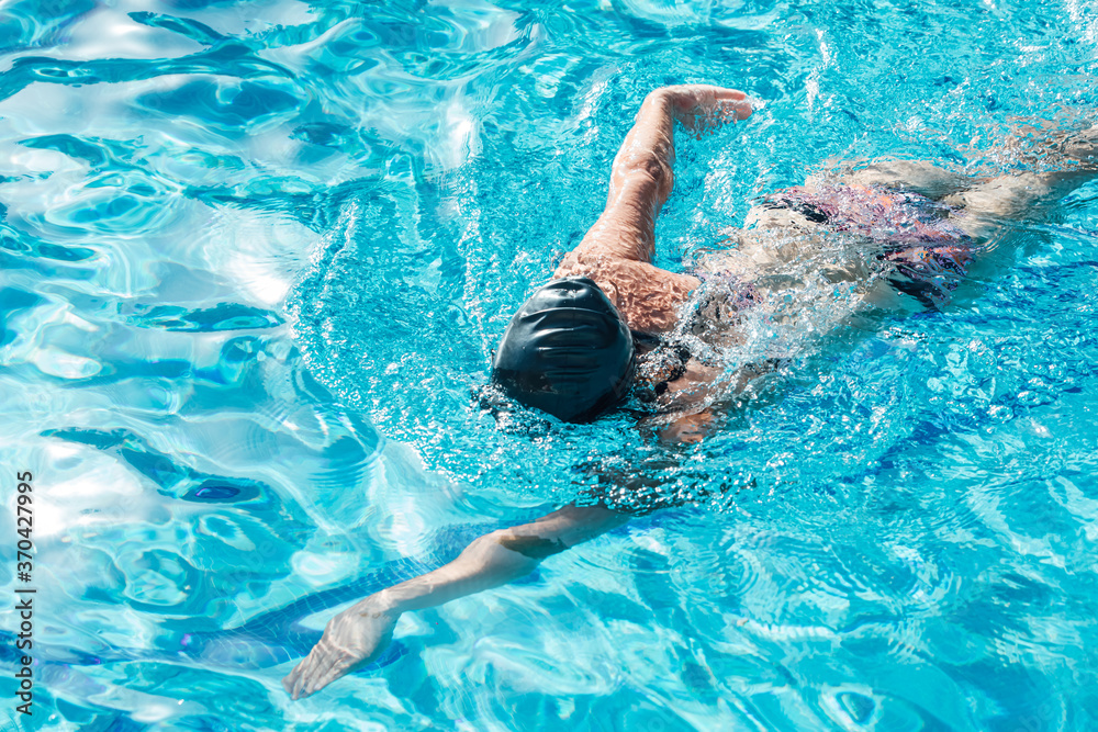 Woman with swimming cap and goggles swimming in a pool