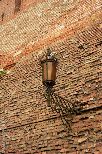 An ancient forged lantern on a red brick wall. Ancient fortress, history.