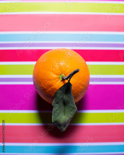 Fresh orange with leaf on colorful tray photo