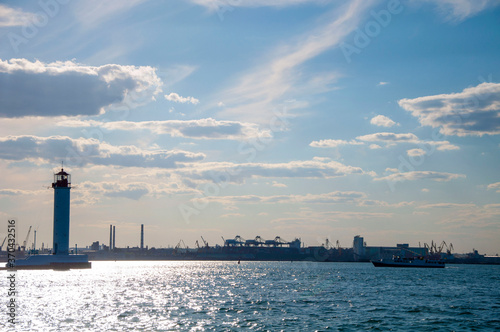 A beautiful lighthouse. View from the sea. Sun in the sky.