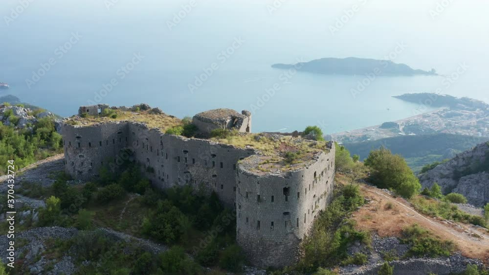 Ruin of an old stone fortress on the top of the hill, overlooking the coast and sea. Fort Kosmac in Montenegro, built by Austro-Hungarians. Aerial view. Ruin of an old stone fortress on the top of the hill, overlooking the coast and sea. Fort Kosmac in Montenegro, built by Austro-Hungarians. Aerial view.