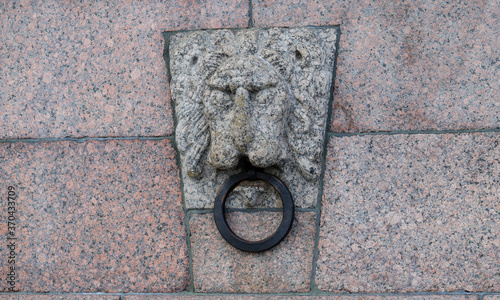 a granite lion with a metal ring in its mouth,