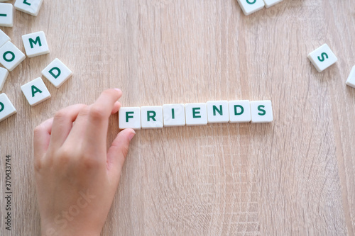 children make up the word friends from letters on a wooden table, the concept of the beginning of the school year, homework, lessons, back to school photo