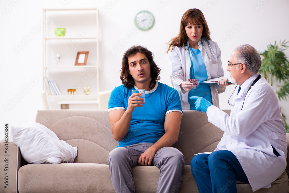 Two doctors visiting sick young man at home Two doctors visiting sick young man at home