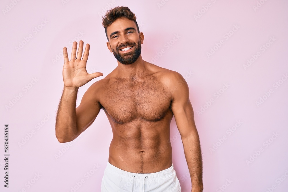 Young hispanic man standing shirtless showing and pointing up with fingers number five while smiling confident and happy. Young hispanic man standing shirtless showing and pointing up with fingers number five while smiling confident and happy.