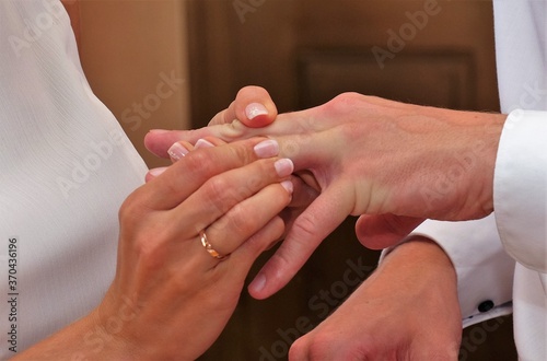  bride puts the wedding ring on the groom's finger 
