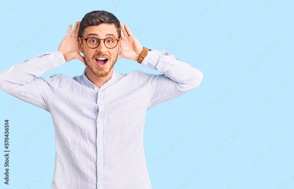 Handsome young man with bear wearing elegant business shirt and glasses smiling cheerful playing peek a boo with hands showing face. surprised and exited Handsome young man with bear wearing elegant business shirt and glasses smiling cheerful playing peek a boo with hands showing face. surprised and exited
