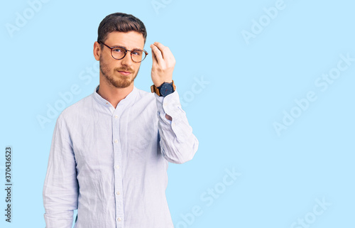 Handsome young man with bear wearing elegant business shirt and glasses doing italian gesture with hand and fingers confident expression