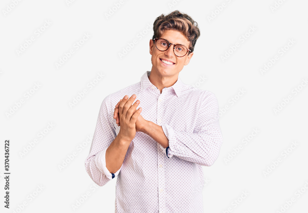 Young handsome man wearing business clothes and glasses clapping and applauding happy and joyful, smiling proud hands together
