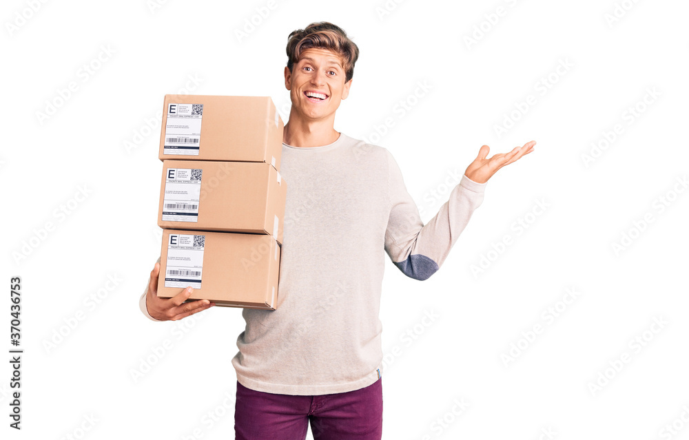 Young handsome man holding delivery package celebrating victory with happy smile and winner expression with raised hands Young handsome man holding delivery package celebrating victory with happy smile and winner expression with raised hands