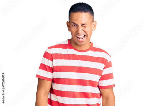 Young handsome latin man wearing casual clothes winking looking at the camera with sexy expression, cheerful and happy face.