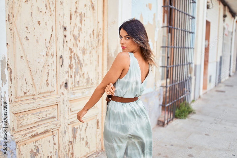 Fototapeta premium Beautiful young woman wearing fashionable clothes walking down the street