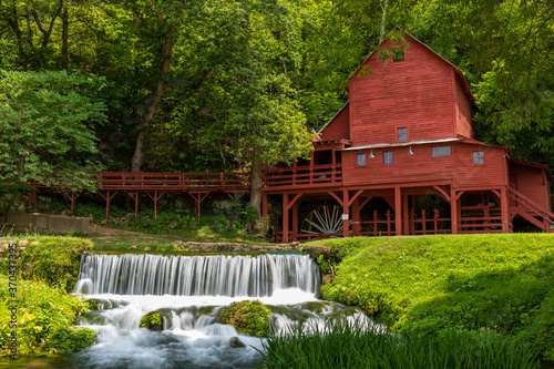 An old red grist mill with a small waterfall.