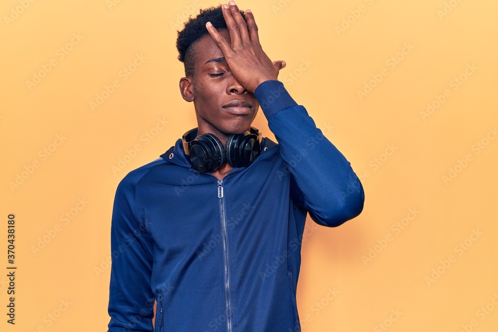 Young african american man wearing sportswear and headphones surprised with hand on head for mistake, remember error. forgot, bad memory concept. Young african american man wearing sportswear and headphones surprised with hand on head for mistake, remember error. forgot, bad memory concept.
