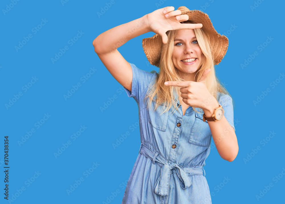 Young beautiful blonde woman wearing summer hat and dress smiling making frame with hands and fingers with happy face. creativity and photography concept. Young beautiful blonde woman wearing summer hat and dress smiling making frame with hands and fingers with happy face. creativity and photography concept.
