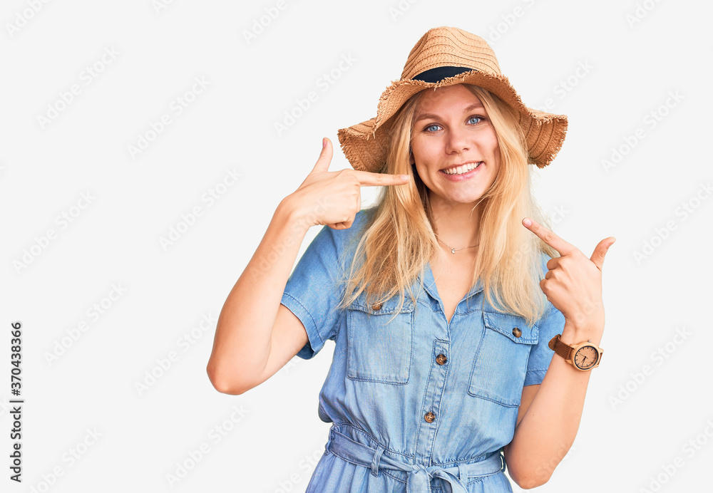 Young beautiful blonde woman wearing summer hat and dress smiling cheerful showing and pointing with fingers teeth and mouth. dental health concept. Young beautiful blonde woman wearing summer hat and dress smiling cheerful showing and pointing with fingers teeth and mouth. dental health concept.