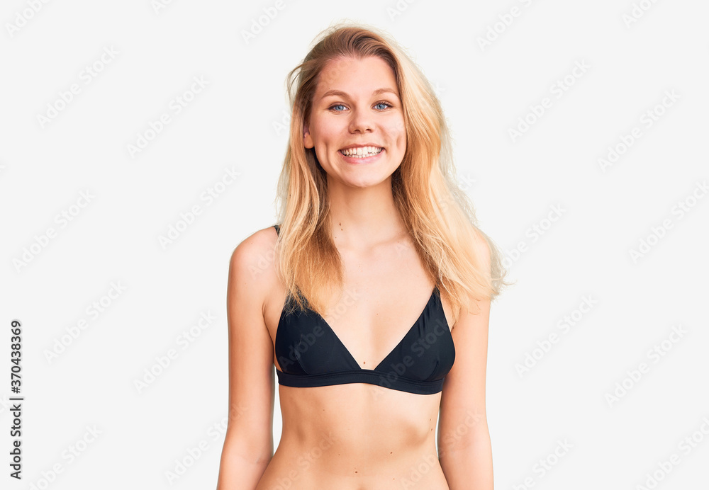 Young beautiful blonde woman wearing bikini with a happy and cool smile on face. lucky person. Young beautiful blonde woman wearing bikini with a happy and cool smile on face. lucky person.