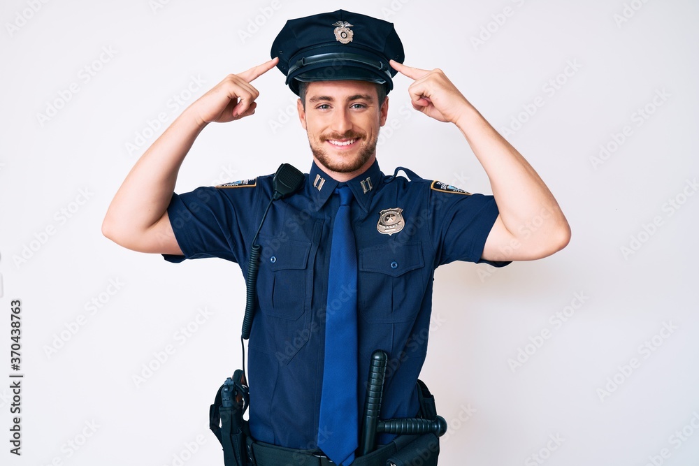 Young caucasian man wearing police uniform smiling pointing to head with both hands finger, great idea or thought, good memory Young caucasian man wearing police uniform smiling pointing to head with both hands finger, great idea or thought, good memory