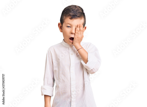 Cute blond kid wearing elegant shirt yawning tired covering half face, eye and mouth with hand. face hurts in pain.