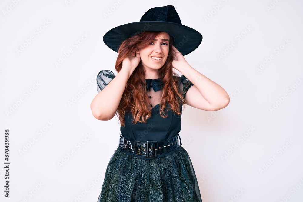 Young beautiful woman wearing witch halloween costume trying to hear both hands on ear gesture, curious for gossip. hearing problem, deaf Young beautiful woman wearing witch halloween costume trying to hear both hands on ear gesture, curious for gossip. hearing problem, deaf