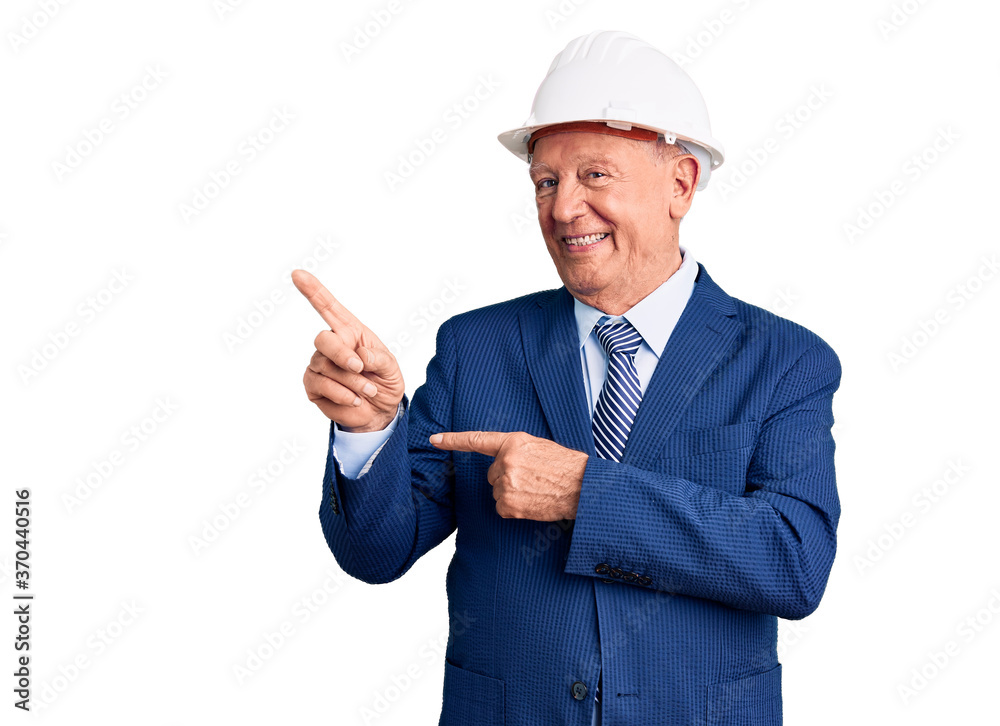 Senior handsome grey-haired man wearing suit and architect hardhat smiling and looking at the camera pointing with two hands and fingers to the side. Senior handsome grey-haired man wearing suit and architect hardhat smiling and looking at the camera pointing with two hands and fingers to the side.