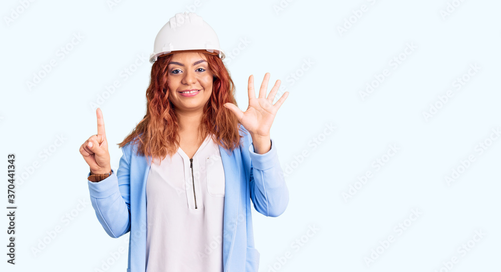 Young latin woman wearing architect hardhat showing and pointing up with fingers number six while smiling confident and happy. Young latin woman wearing architect hardhat showing and pointing up with fingers number six while smiling confident and happy.