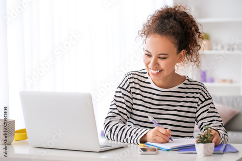 Young woman using laptop for online learning at home photo