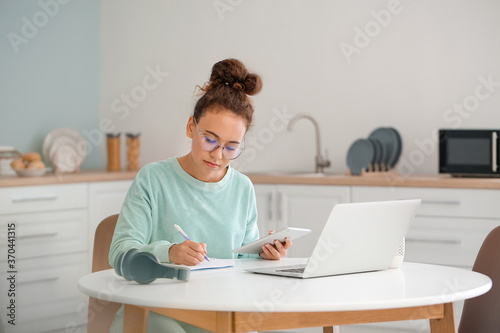 Young woman using tablet computer and laptop for online learning at home