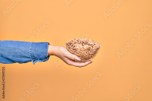 Photo Hand of caucasian young woman holding bowl with cornflakes cereal over isolated