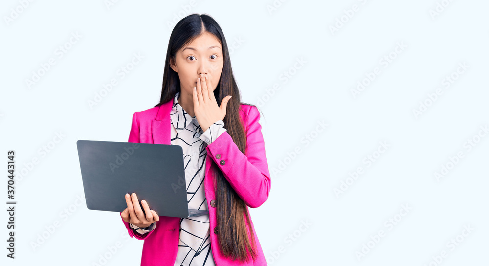 Young beautiful chinese woman using laptop covering mouth with hand, shocked and afraid for mistake. surprised expression Young beautiful chinese woman using laptop covering mouth with hand, shocked and afraid for mistake. surprised expression