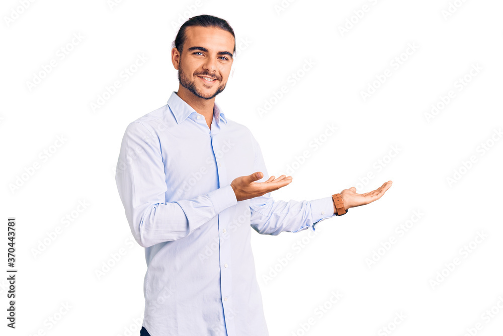 Young handsome man wearing business clothes inviting to enter smiling natural with open hand Young handsome man wearing business clothes inviting to enter smiling natural with open hand