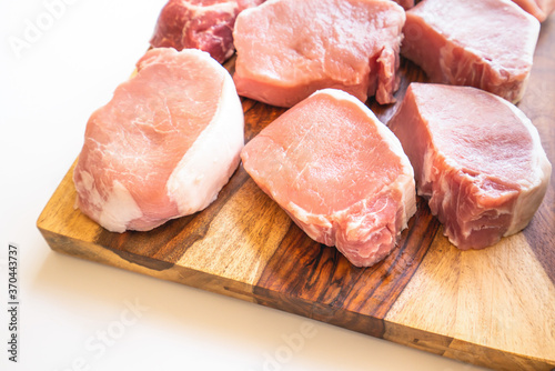 Boneless raw pork loin chops close up on wooden cutting board