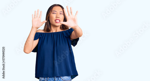 Young beautiful chinese girl wearing casual clothes afraid and terrified with fear expression stop gesture with hands, shouting in shock. panic concept.