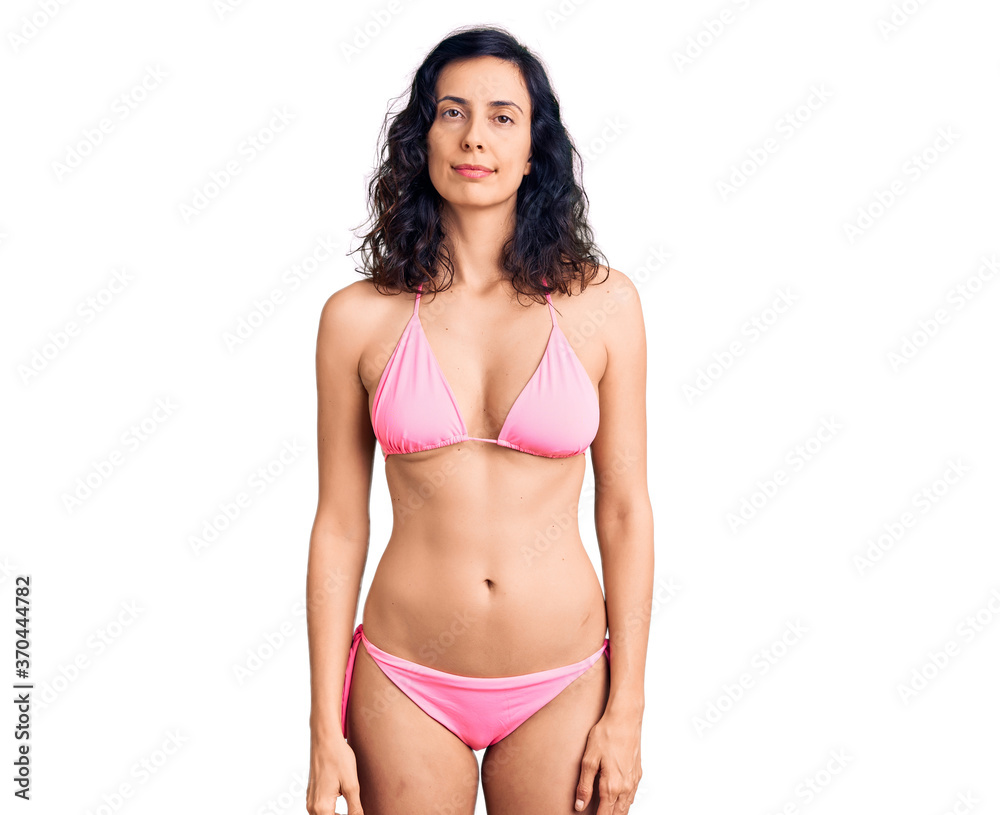 Young beautiful hispanic woman wearing bikini relaxed with serious expression on face. simple and natural looking at the camera. Young beautiful hispanic woman wearing bikini relaxed with serious expression on face. simple and natural looking at the camera.