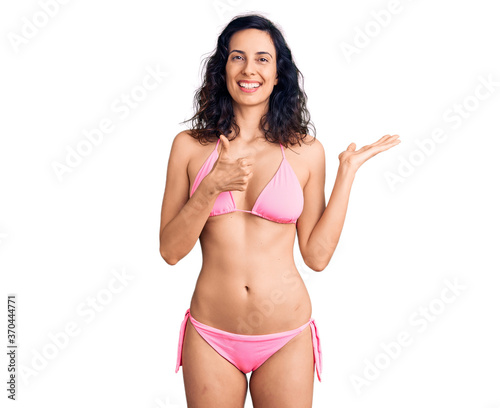 Young beautiful hispanic woman wearing bikini showing palm hand and doing ok gesture with thumbs up, smiling happy and cheerful © Krakenimages.com