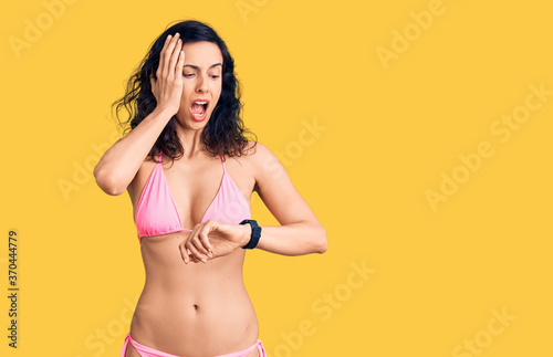Young beautiful hispanic woman wearing bikini looking at the watch time worried, afraid of getting late © Krakenimages.com