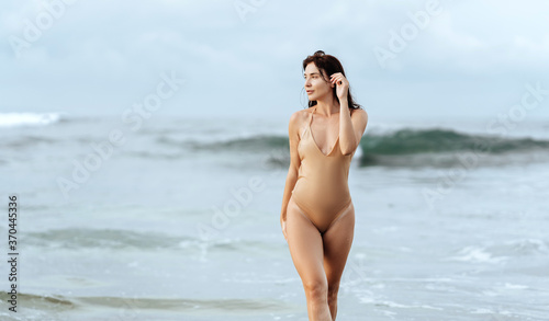 Outdoor summer fashion portrait of pretty sexy young woman in bikini posing behind blue ocean © Margo Basarab