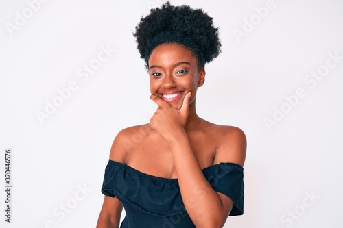 Young african american woman wearing casual clothes looking confident at the camera smiling with crossed arms and hand raised on chin. thinking positive.