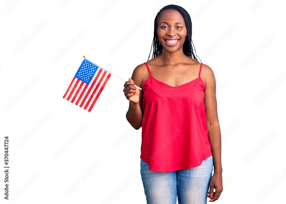 Young african american woman holding united states flag looking positive and happy standing and smiling with a confident smile showing teeth Young african american woman holding united states flag looking positive and happy standing and smiling with a confident smile showing teeth