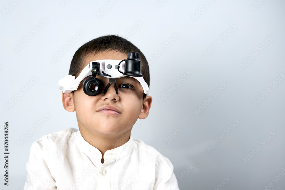 Little boy looking through special magnifying eyeglasses