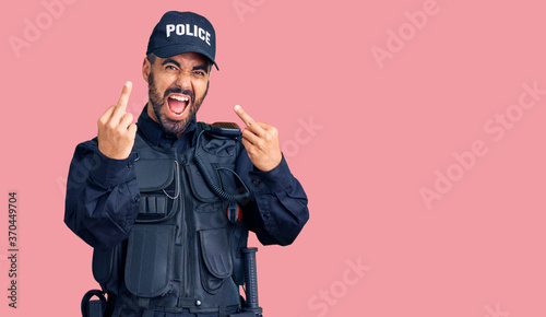 Fotografija Young hispanic man wearing police uniform showing middle finger doing fuck you bad expression, provocation and rude attitude