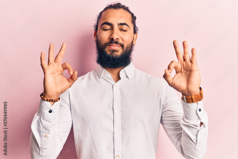 Young arab man wearing casual clothes relax and smiling with eyes closed doing meditation gesture with fingers. yoga concept. Young arab man wearing casual clothes relax and smiling with eyes closed doing meditation gesture with fingers. yoga concept.