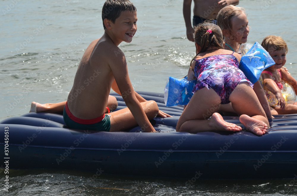 Obraz premium Caucasian children outdoor in summer swimming with inflatable mattress