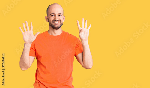 Young handsome man wering casual t shirt showing and pointing up with fingers number nine while smiling confident and happy.