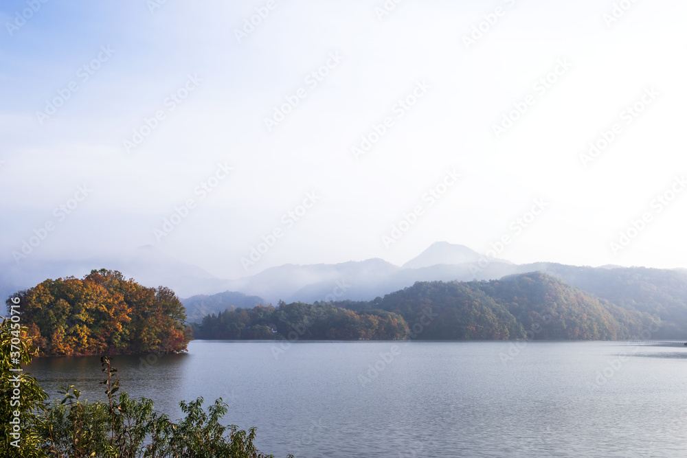 Obraz premium Beautiful autumn scenery,foggy mist over the lake and mountain.