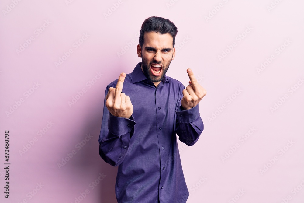 Young handsome man with beard wearing casual shirt showing middle finger doing fuck you bad expression, provocation and rude attitude. screaming excited Young handsome man with beard wearing casual shirt showing middle finger doing fuck you bad expression, provocation and rude attitude. screaming excited