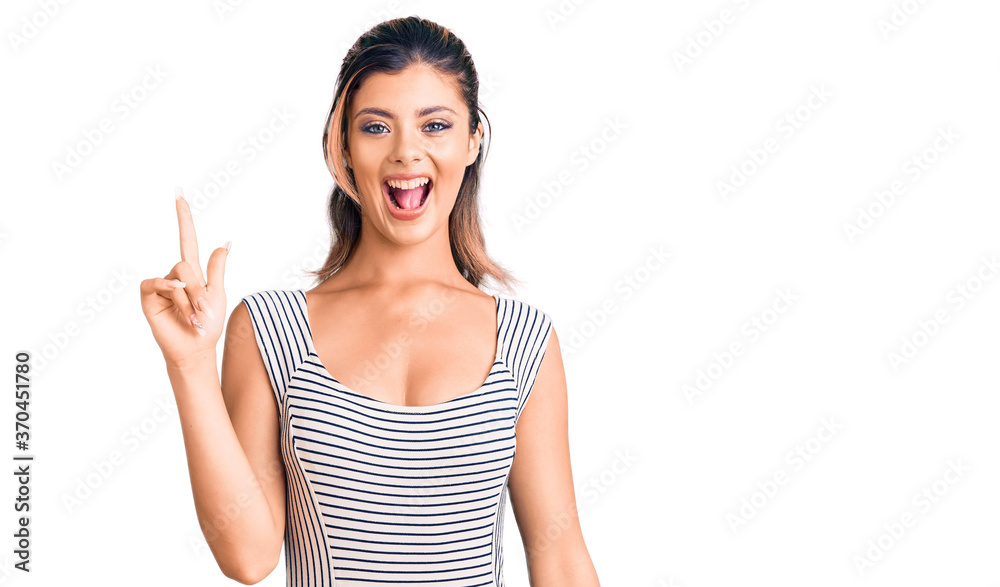 Young beautiful woman wearing casual dress pointing finger up with successful idea. exited and happy. number one. Young beautiful woman wearing casual dress pointing finger up with successful idea. exited and happy. number one.