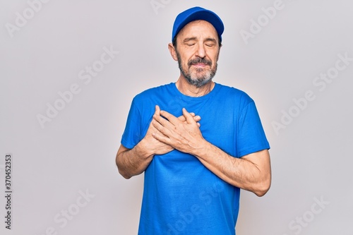 Middle age handsome deliveryman wearing cap standing over isolated white background smiling with hands on chest, eyes closed with grateful gesture on face. Health concept.