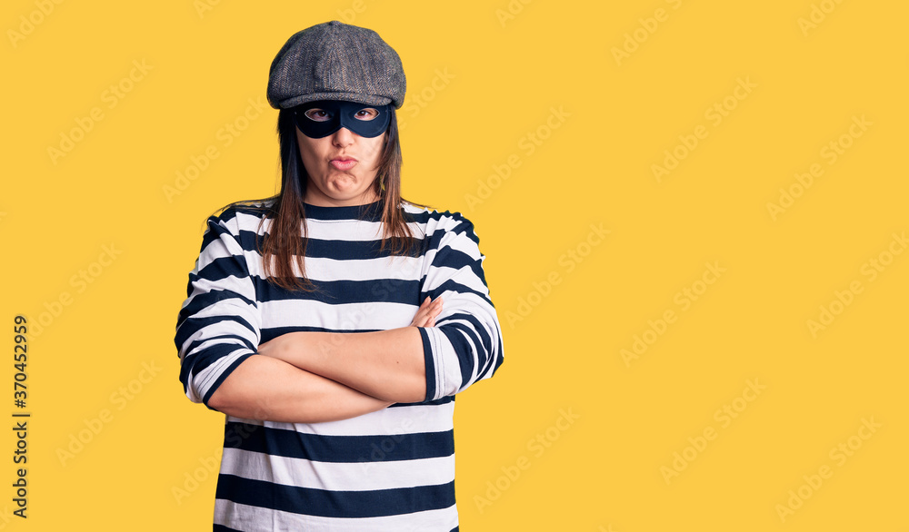Young beautiful brunette woman wearing burglar mask skeptic and nervous, disapproving expression on face with crossed arms. negative person.